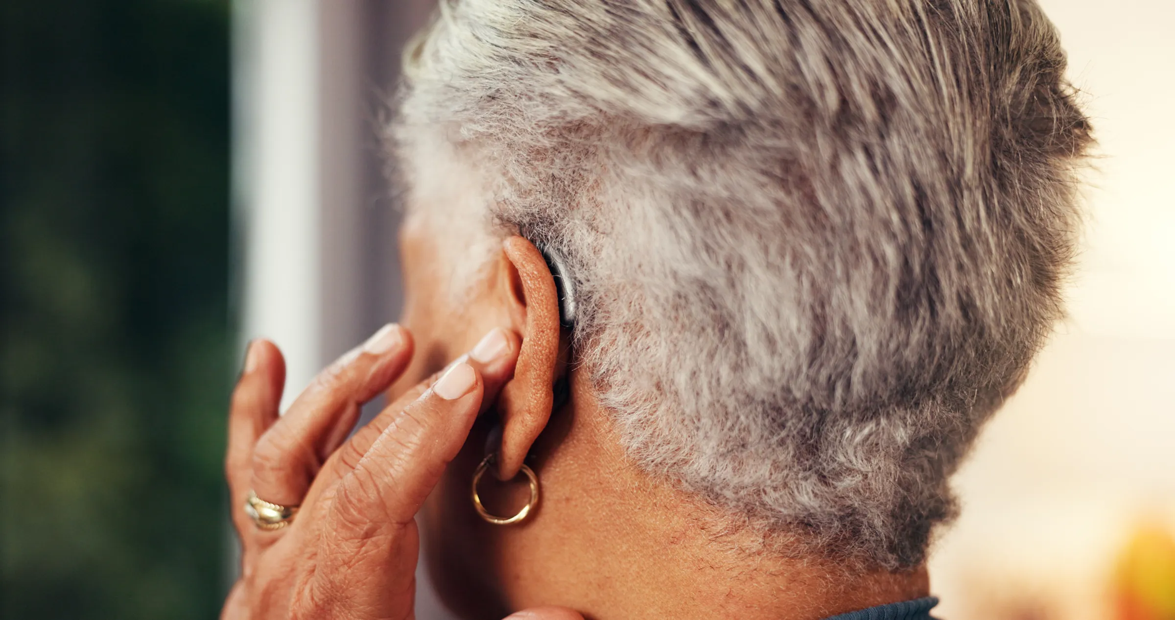 Home, back and senior woman with hearing aid, testing and comfort with retirement. Hand, pensioner and elderly person with disability, medical audio tech and deaf with innovation and fitting mould